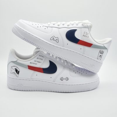Paar weiße Nike Air Force 1 Custom Sneaker mit blau-rotem Swoosh-Design und Hobby-Symbolen wie Gaming-Controller Hantel und Fußball, Schriftzug EST 2003