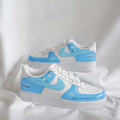 Weiße Nike Air Force 1 Sneakers mit blauen Akzenten und Schriftzug auf der Seite.