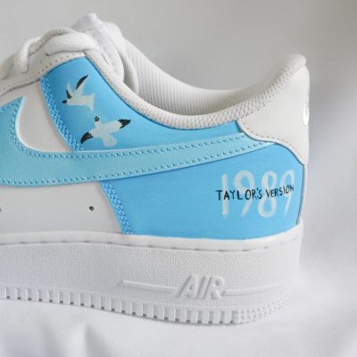 Weiß-blaue Sneakers mit dem Aufdruck 'Taylor's Version' und Vögeln auf der Seite.