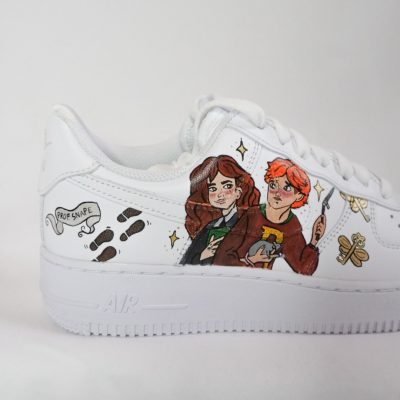 Weißes Sneaker-Modell mit Illustrationen von zwei Charakteren auf der Seite.