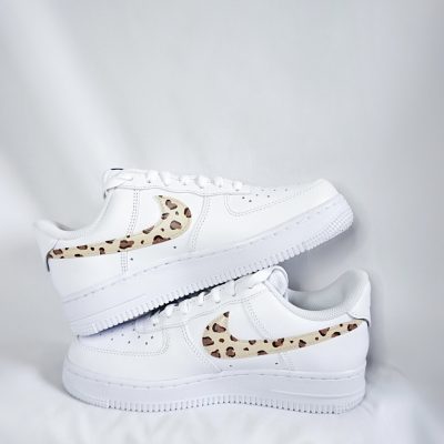 Weiße Nike Air Force 1 Sneakers mit einem braunen Tiermuster auf der Seite.