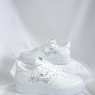 Weiße Sneakers mit einem handgezeichneten Motiv auf der Seite, auf einem weißen Hintergrund.
