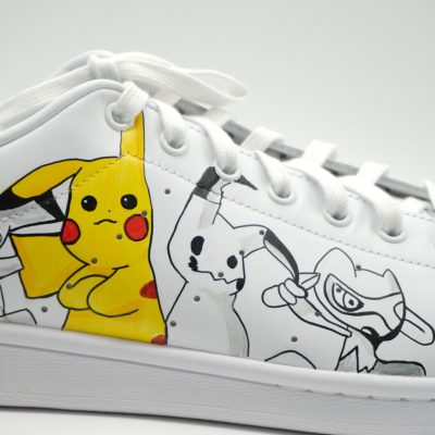 Weißer Sneaker mit handgezeichneten Pikachu- und Pokémon-Motiven auf der Seite.