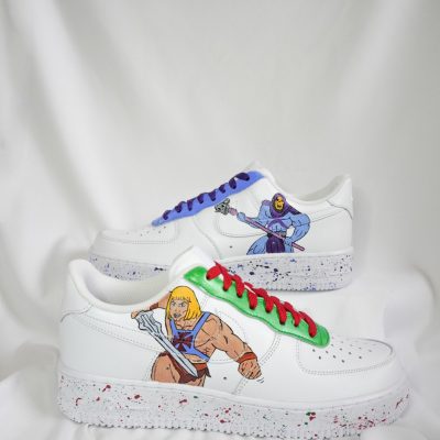 Weiße Sneaker mit He-Man und Skeletor Grafiken auf der Seite und bunten Schnürsenkeln.